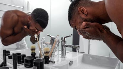 persona lavándose la cara en el baño