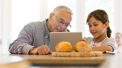 Abuelo usando laptop con niña