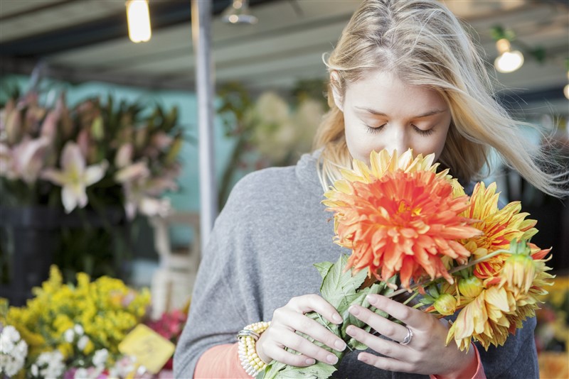 una mujer oliendo flores