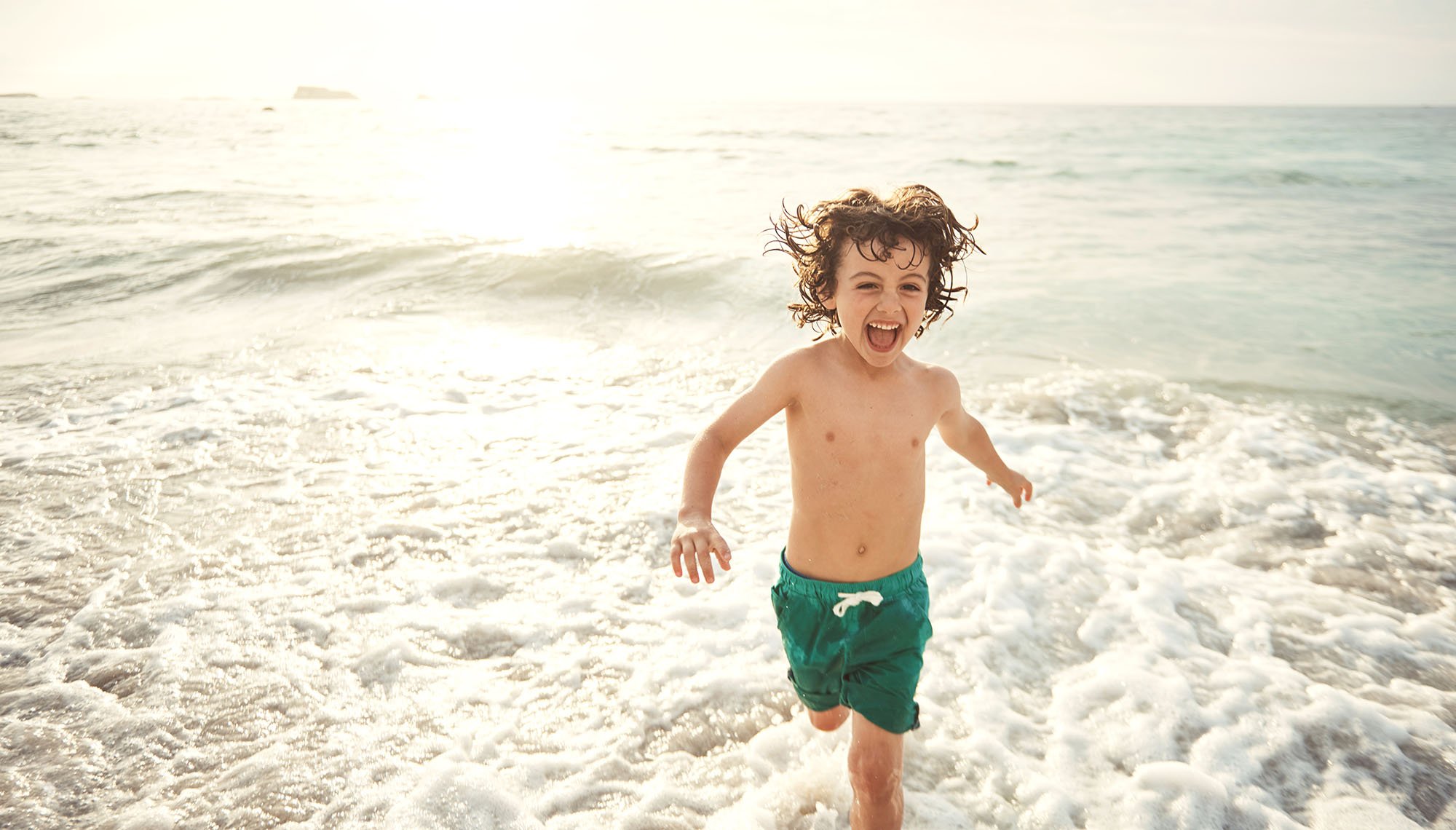 Chico joven corriendo a lo largo de la playa