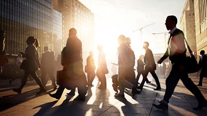 Empleados caminando al trabajo en la ciudad al amanecer.